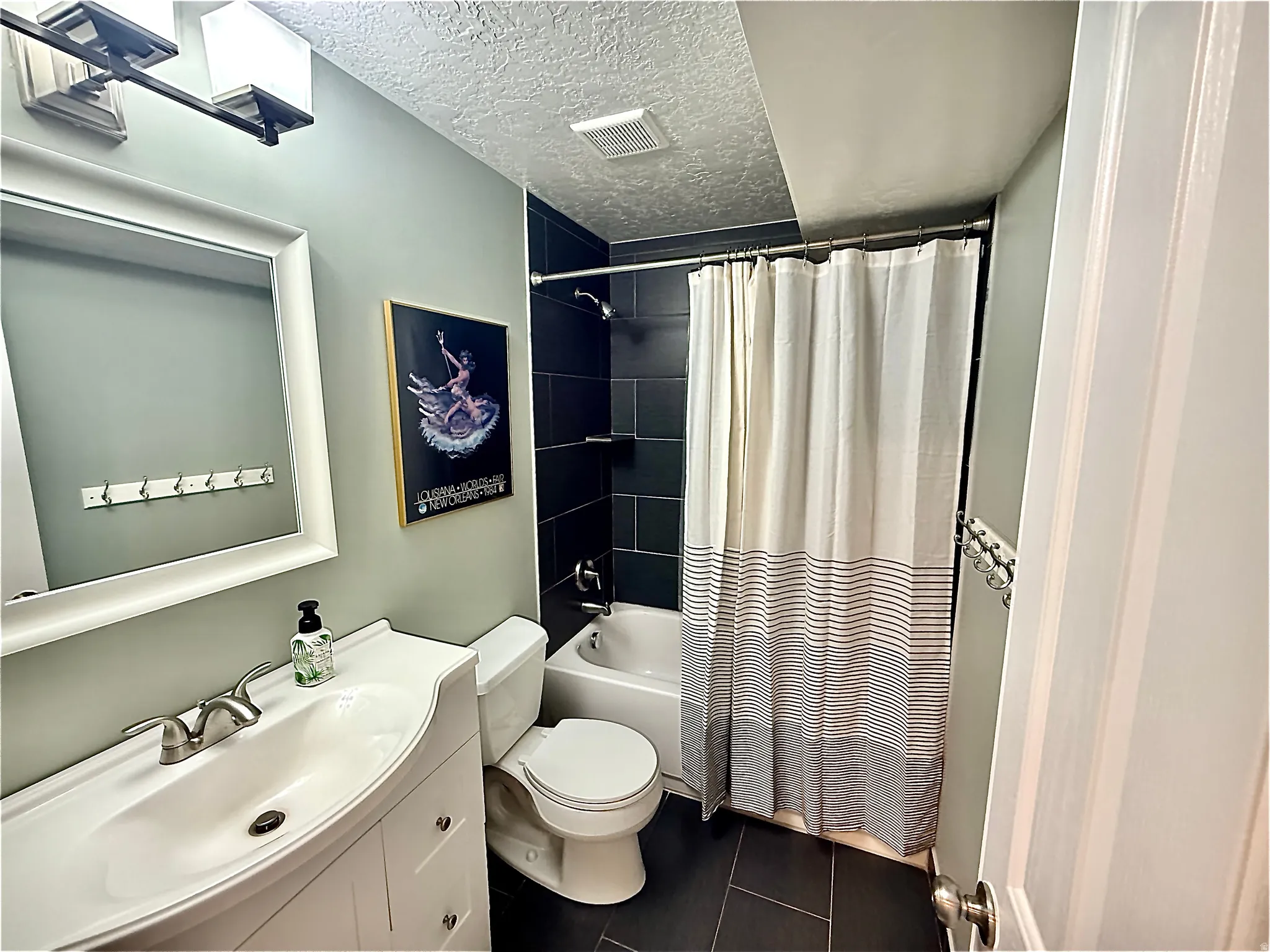 White vanity with integrated sink, brushed nickel faucet, large framed mirror, and overhead vanity lighting