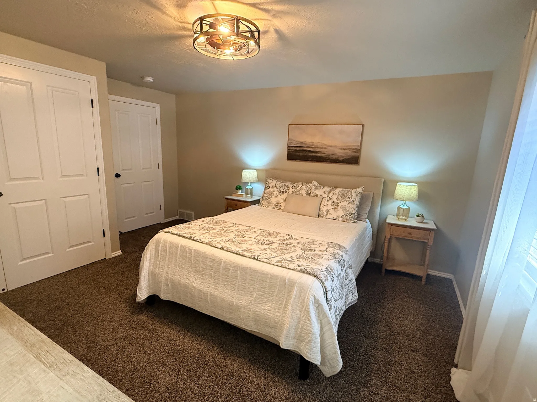 Ceiling fan light fixture, neutral wall color, white paneled doors, and brown carpet flooring