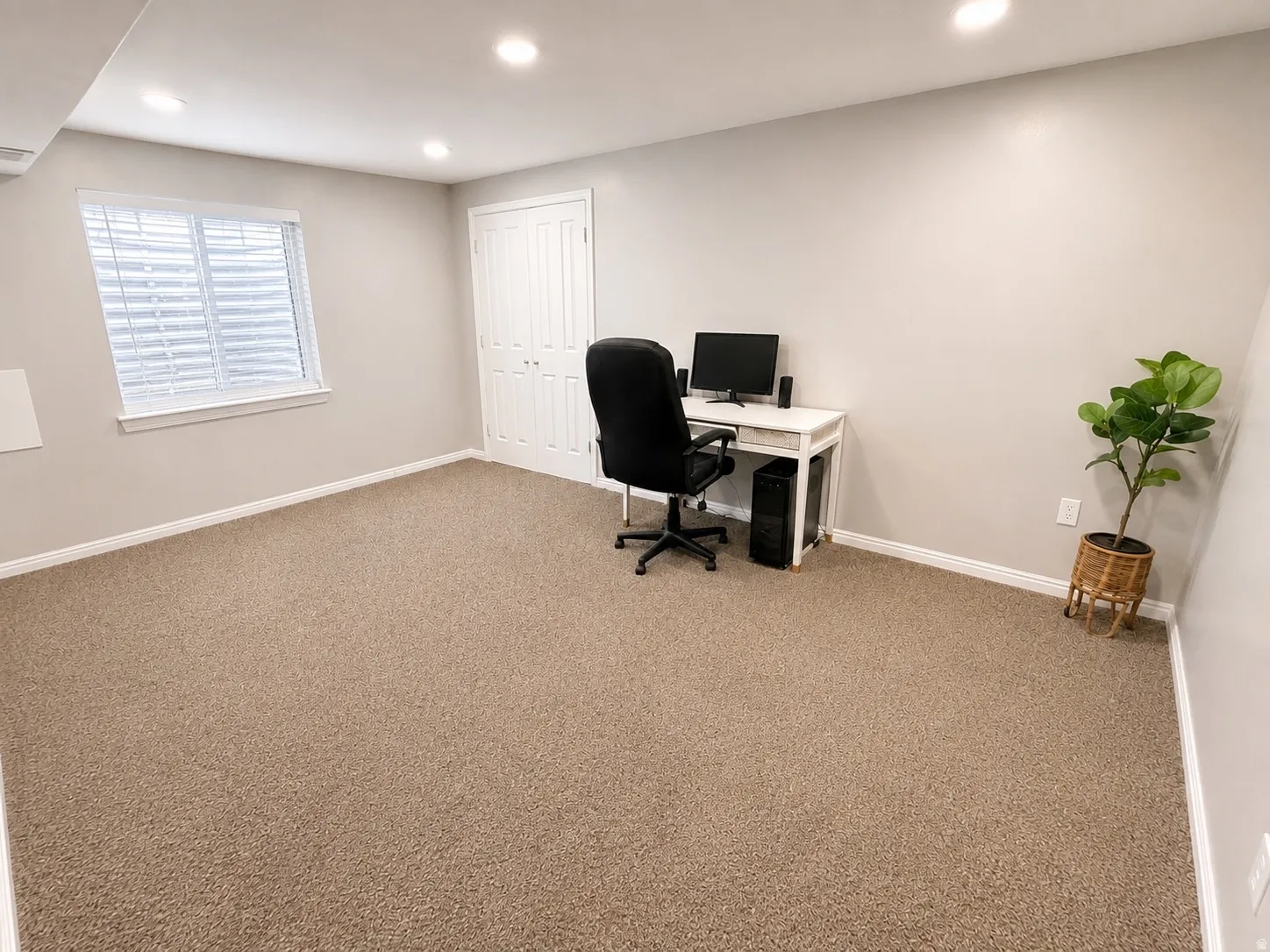 Spacious room featuring neutral carpeting, recessed lighting, a window with blinds, and white bi-fold closet doors