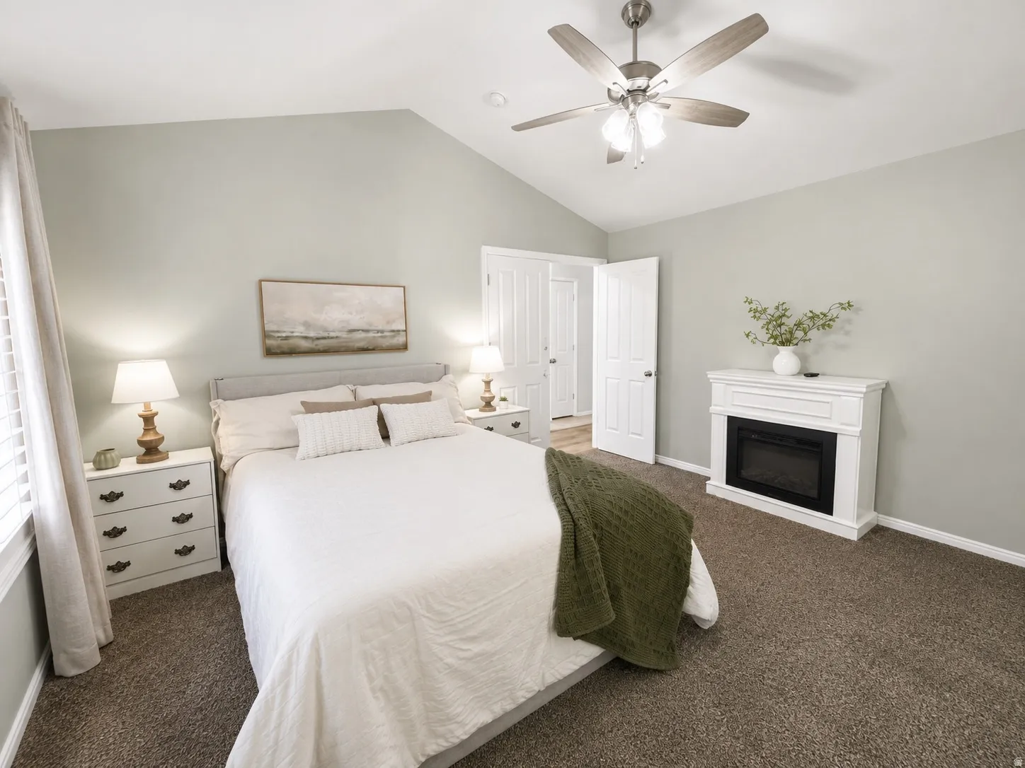 Vaulted ceiling with a ceiling fan, white paneled doors, and a decorative fireplace