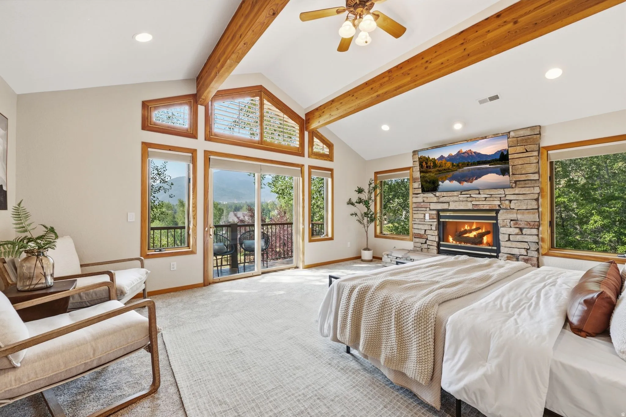 Primary bedroom featuring exposed wooden beams, private balcony, fireplace, seating area, ensuite bathroom with heated floors, a jetted tub, stand alone shower, and walk-in closet.  Wake up to the incredible views of the mountains.