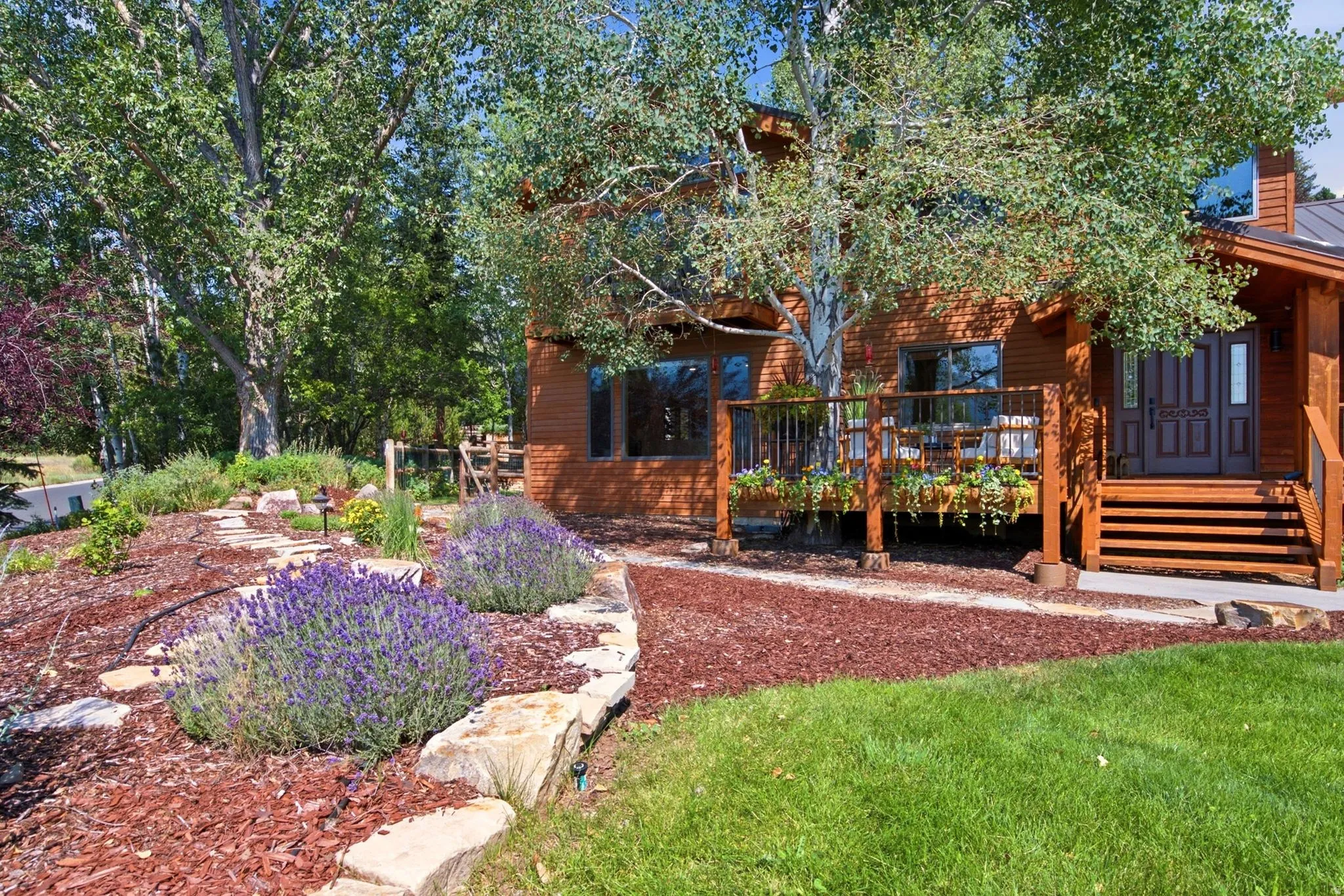 Front exterior featuring the primary bedroom balcony, front porch, entrance, grass and xeriscaping.