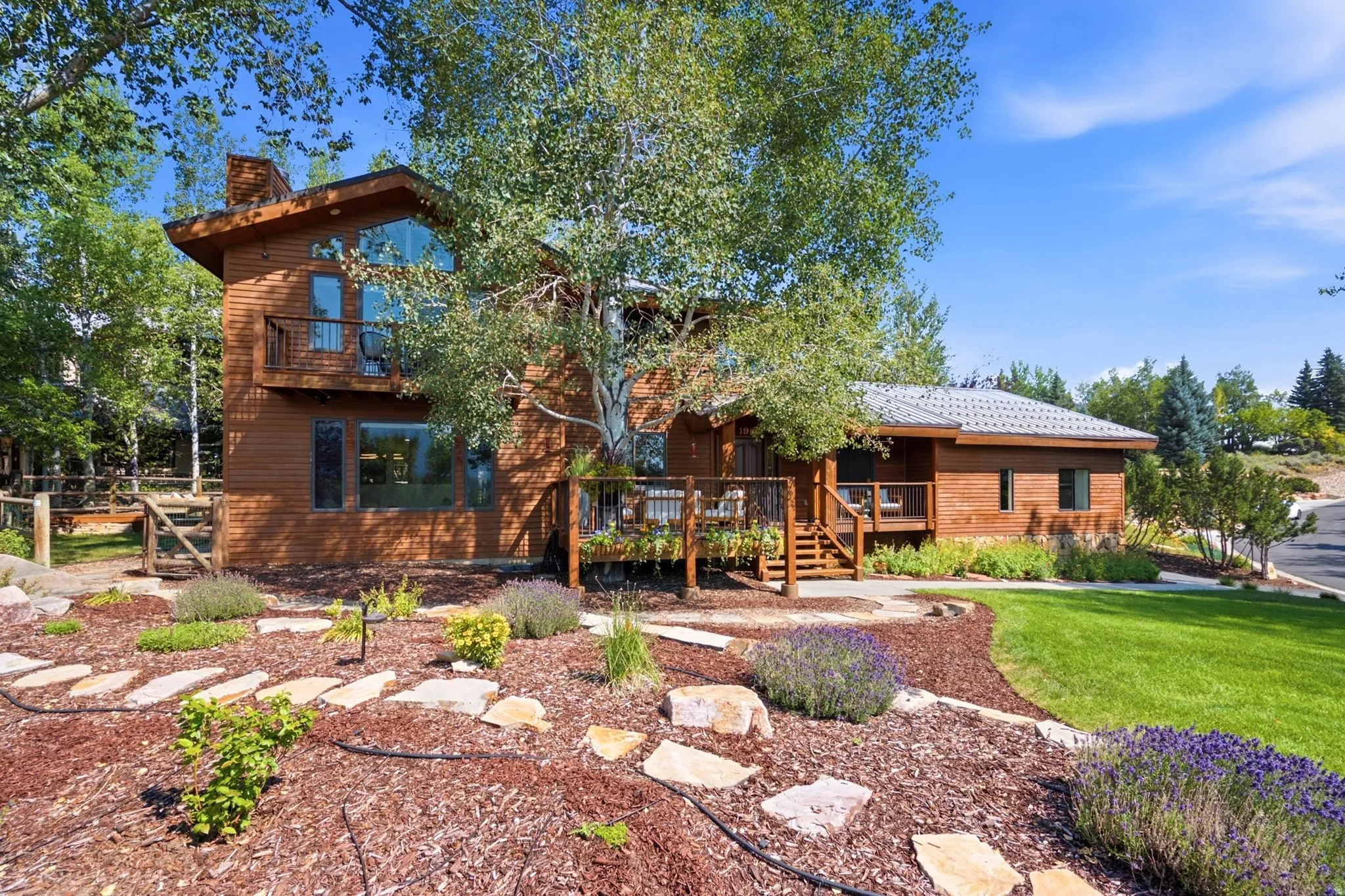 Front exterior featuring the primary bedroom balcony, front porch, entrance, grass and xeriscaping.