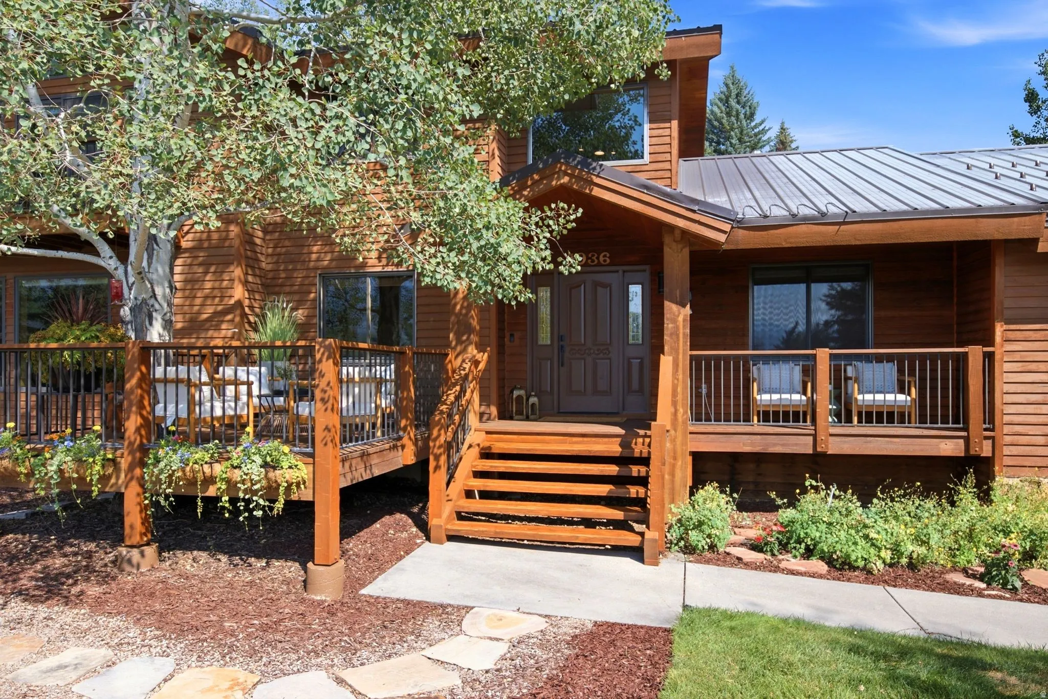 Front exterior entrance view featuring a  seating area and a large front deck built around a tree so you can enjoy the views and be one with nature.