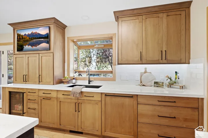 Wood-finish cabinetry with black hardware, white countertops, and a subway tile backsplash