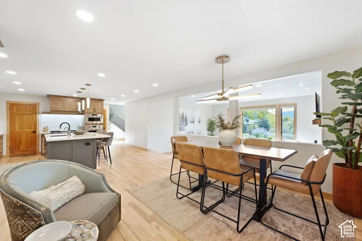 Hardwood flooring throughout, kitchen island with built-in cabinetry, recessed and pendant lighting, and a contemporary dining light fixture