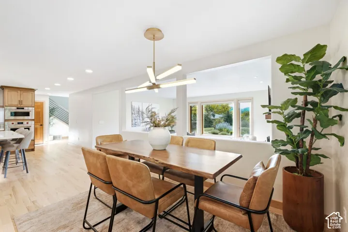 Expansive dining area featuring wood-finish flooring, a contemporary linear chandelier, and a pass-through window opening to an additional living space
