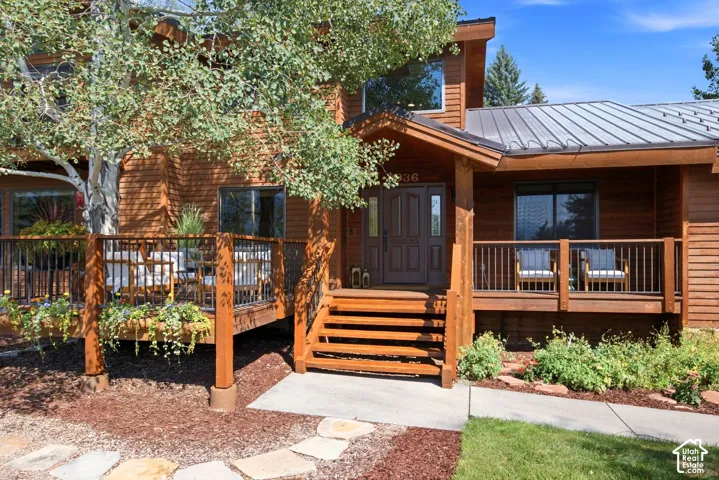 Front exterior entrance view featuring a  seating area and a large front deck built around a tree so you can enjoy the views and be one with nature.