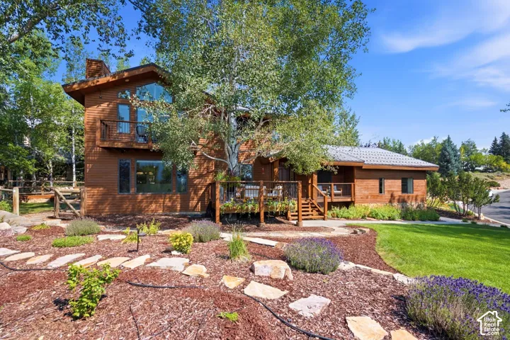Front exterior featuring the primary bedroom balcony, front porch, entrance, grass and xeriscaping.
