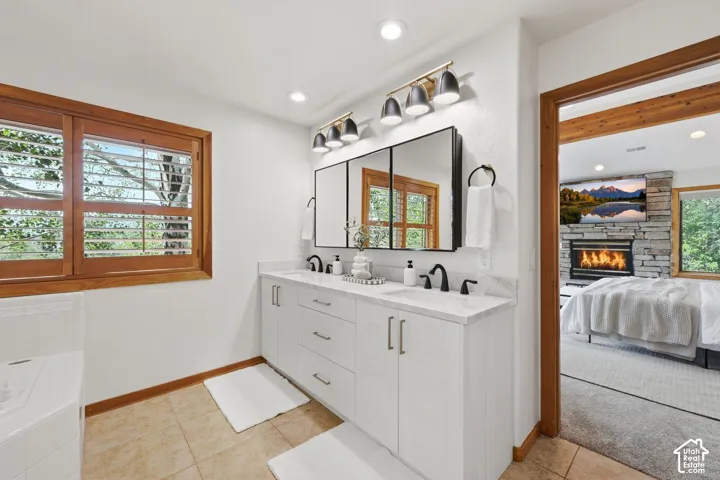 Primary bathroom boasts a jetted tub, heated floors, a stand-alone shower, a walk-in closet, an updated vanity and lighting, and  double sink with Taj Mahal quartzite counters