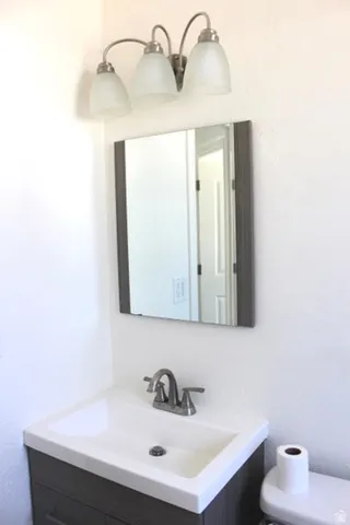 Vanity with integrated sink, brushed nickel faucet, framed mirror, and three-light vanity fixture