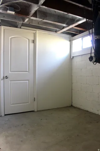 White paneled door, exposed ceiling joists, concrete flooring, and a small window
