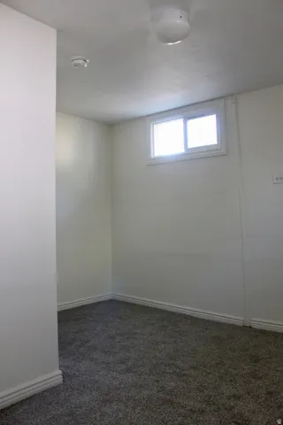 White painted walls with gray carpet flooring and a fixed window