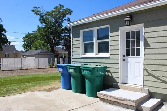 Siding exterior with a white paneled door, exterior lighting fixture, and concrete steps