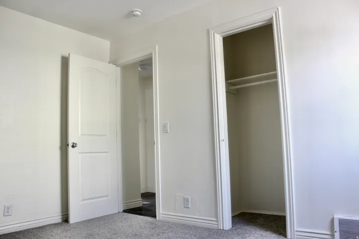 Bedroom featuring multiple closet spaces with white finish doors and shelving, neutral carpeting, and recessed ceiling lighting