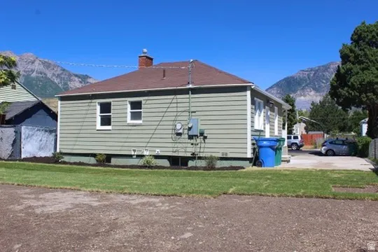 Ranch-style exterior with light green siding, white-trimmed windows, and a brown shingle roof