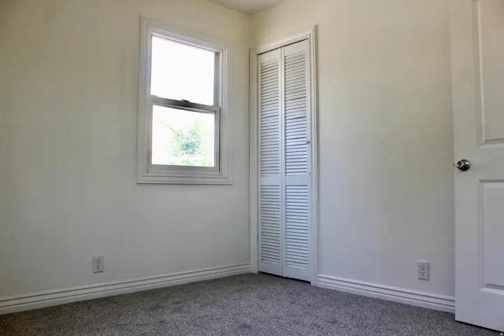 Wall-to-wall carpeting, double-pane window, and louvered bi-fold closet doors