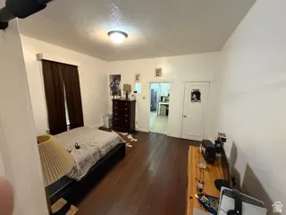 Unit 1 bedroom. Hardwood flooring throughout, overhead flush-mount lighting, and white trim