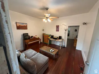 Unit 1 living room. Wood-finish flooring throughout, ceiling fan with integrated lighting, and a wide interior doorway