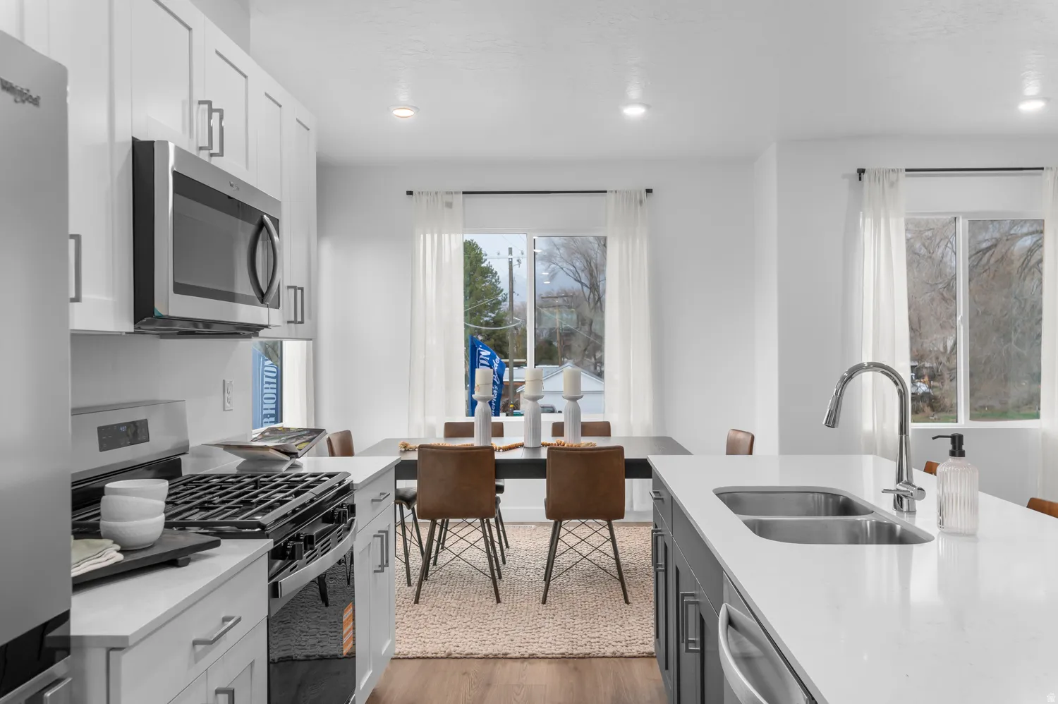 Stainless steel appliances, recessed lighting, white cabinetry, integrated double basin sink, and wood-finish flooring