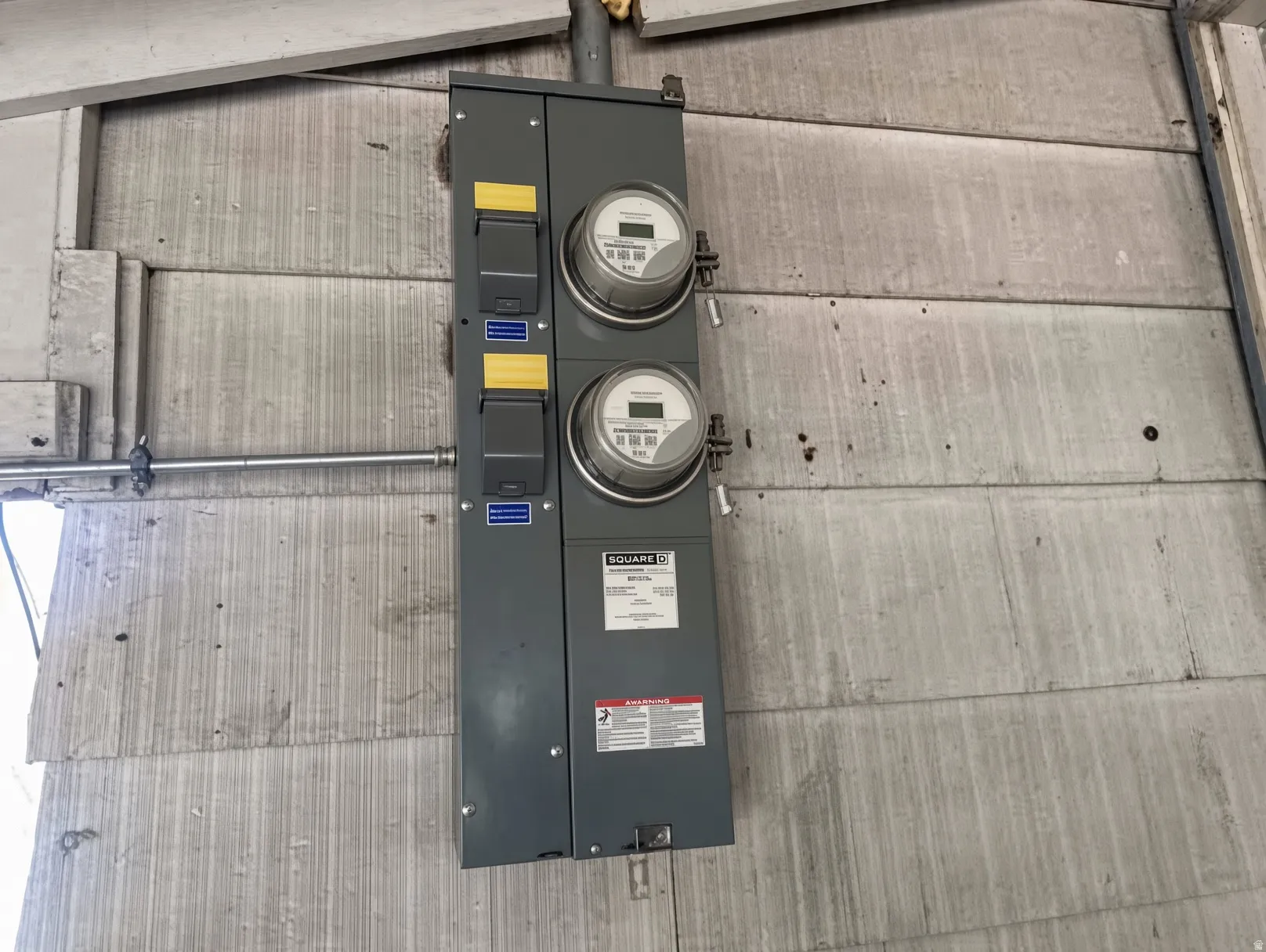 Dual electric meters on a gray exterior wall
