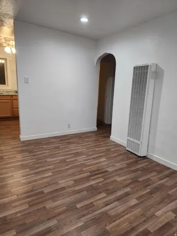 Wood-finish flooring, white walls, recessed ceiling lighting, and an arched doorway