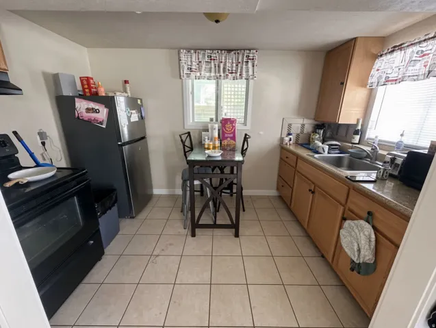 Kitchen with tiled flooring, wood-finish cabinetry, and a stainless steel sink