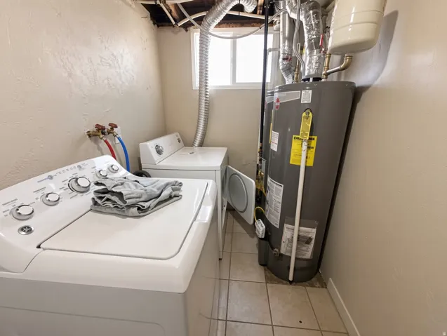 Laundry area featuring a water heater, tiled flooring, and a window