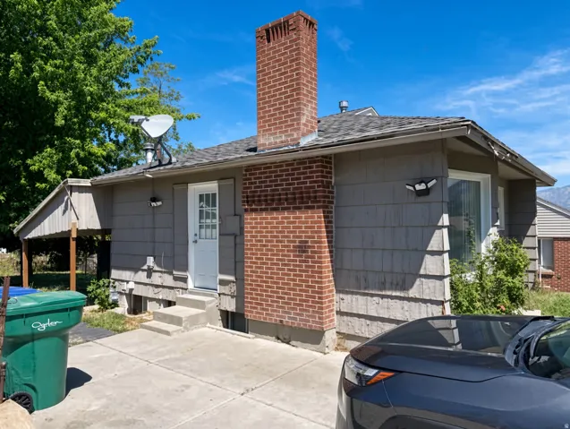 Brick chimney exterior with shingle siding and a covered carport structure