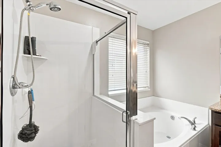 Walk-in shower with a chrome shower head and white paneling