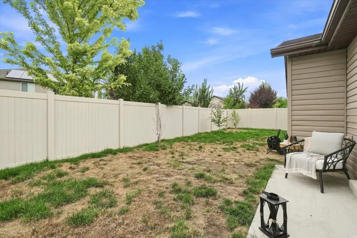Spacious fenced backyard with mature landscaping, established trees, and open lawn space
