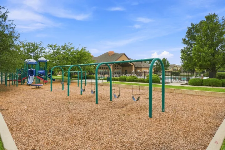 Outdoor playground with wood chip surfacing, multiple swings, and a multi-level play structure featuring slides