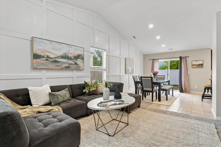 Open-concept living area featuring a dark upholstered sectional sofa, round marble-top accent table, and neutral area rug