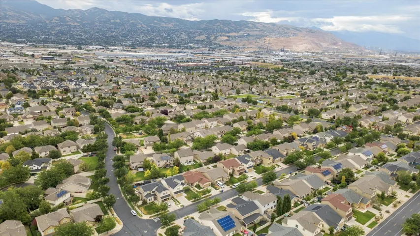 Expansive residential area featuring numerous detached homes, tree-lined streets, and distant mountain ranges
