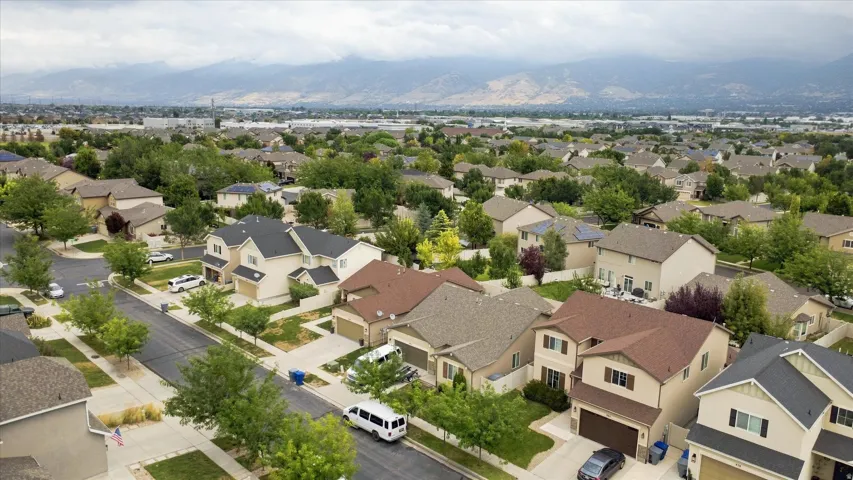 Aerial view showcasing this residential community featuring single-family homes with varied architectural styles, mature landscaping throughout the neighborhood, and mountain backdrop in the distance
