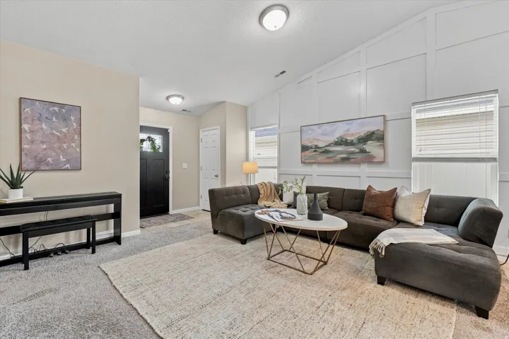 Sophisticated living room showcasing a curved sectional sofa, neutral wood-finish flooring anchored by a natural fiber area rug, and recessed ceiling lighting