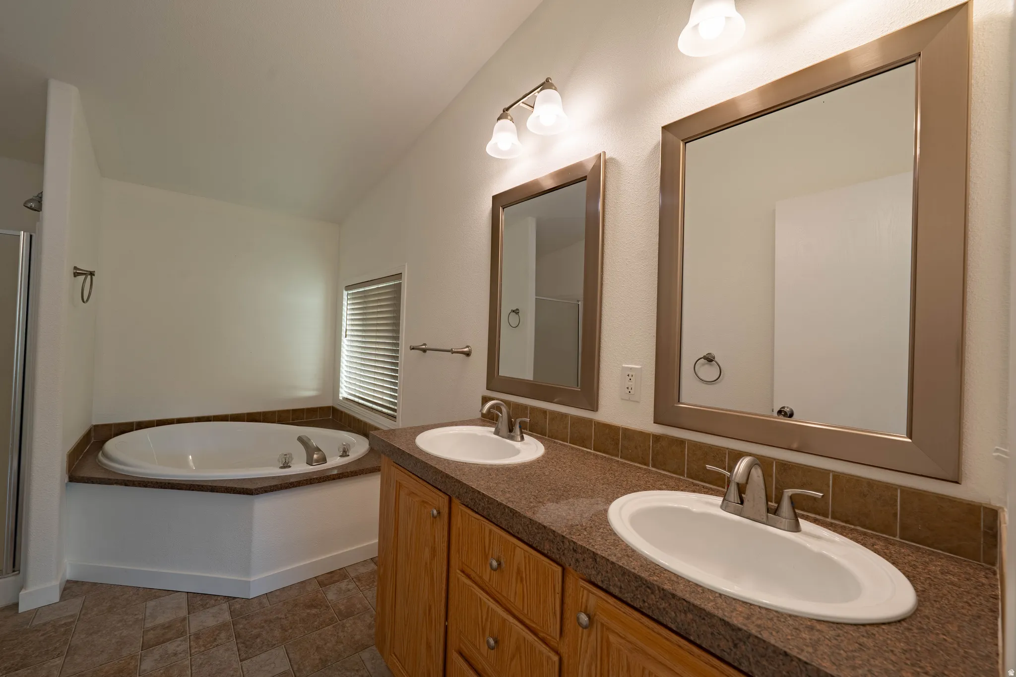 Dual vanity with integrated sinks, framed mirrors, and a built-in jetted tub