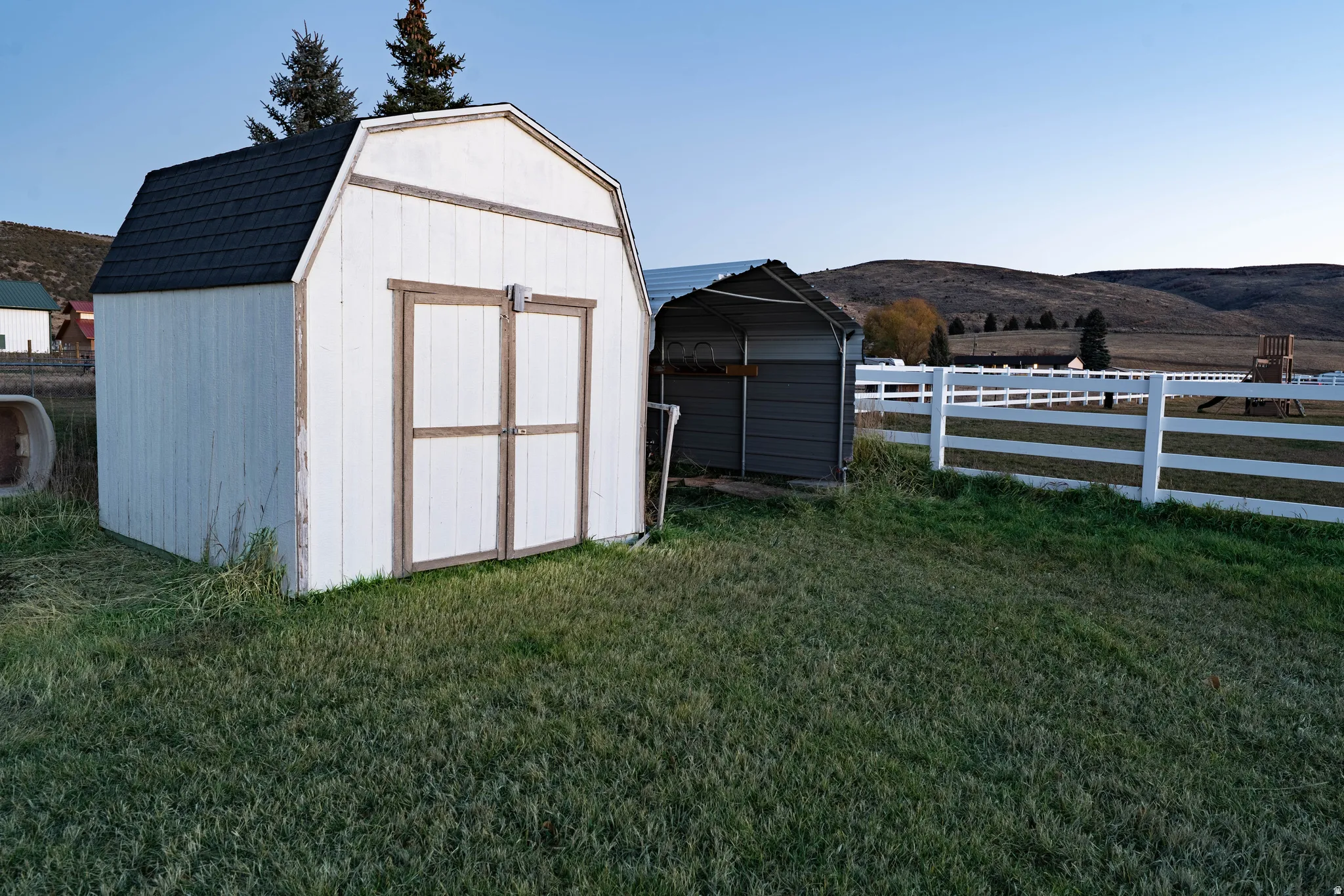 Gabled storage shed with dual barn doors and a dark shingle roof