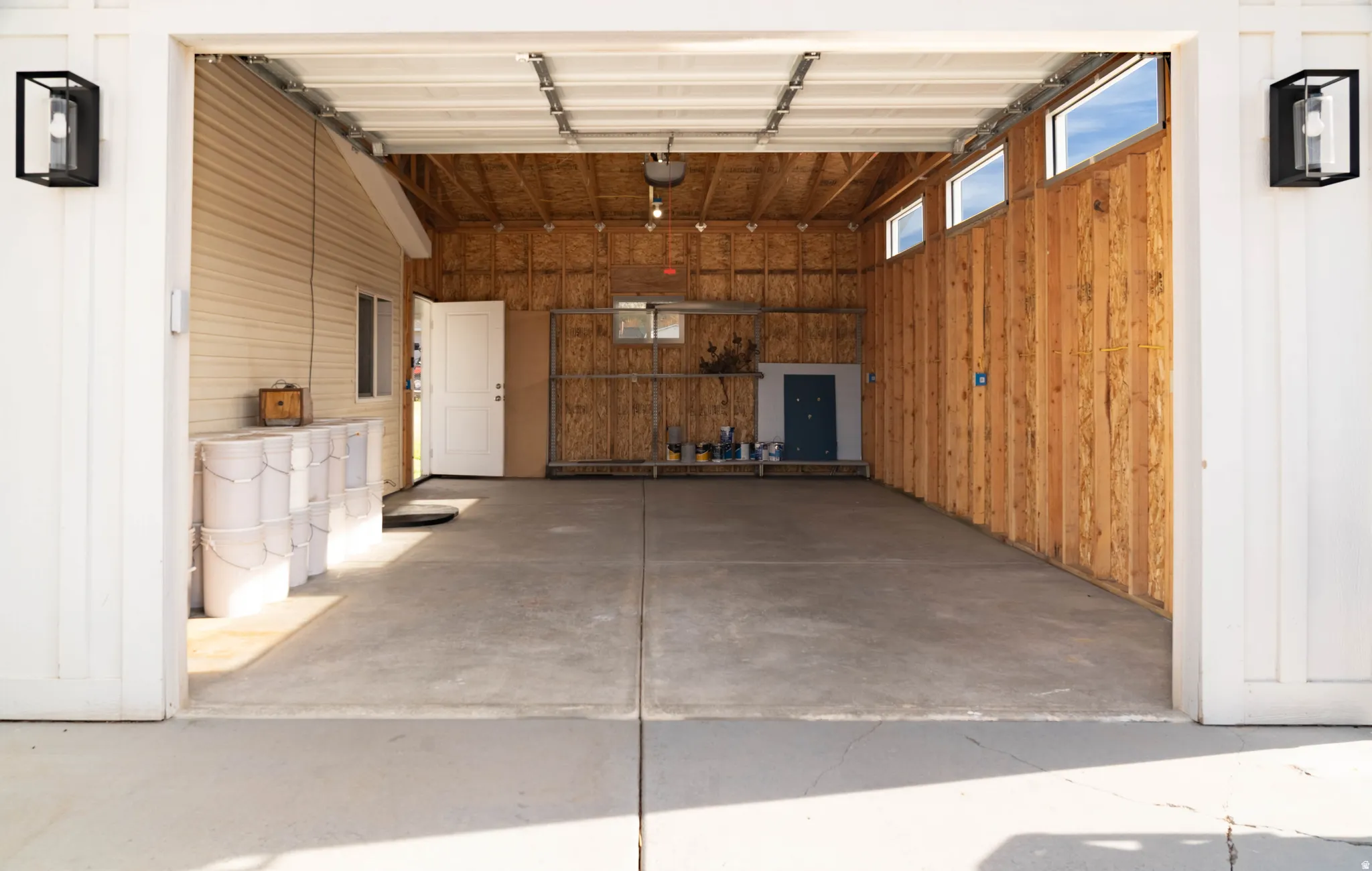 Spacious garage with a concrete floor, horizontal siding, and natural wood-paneled walls