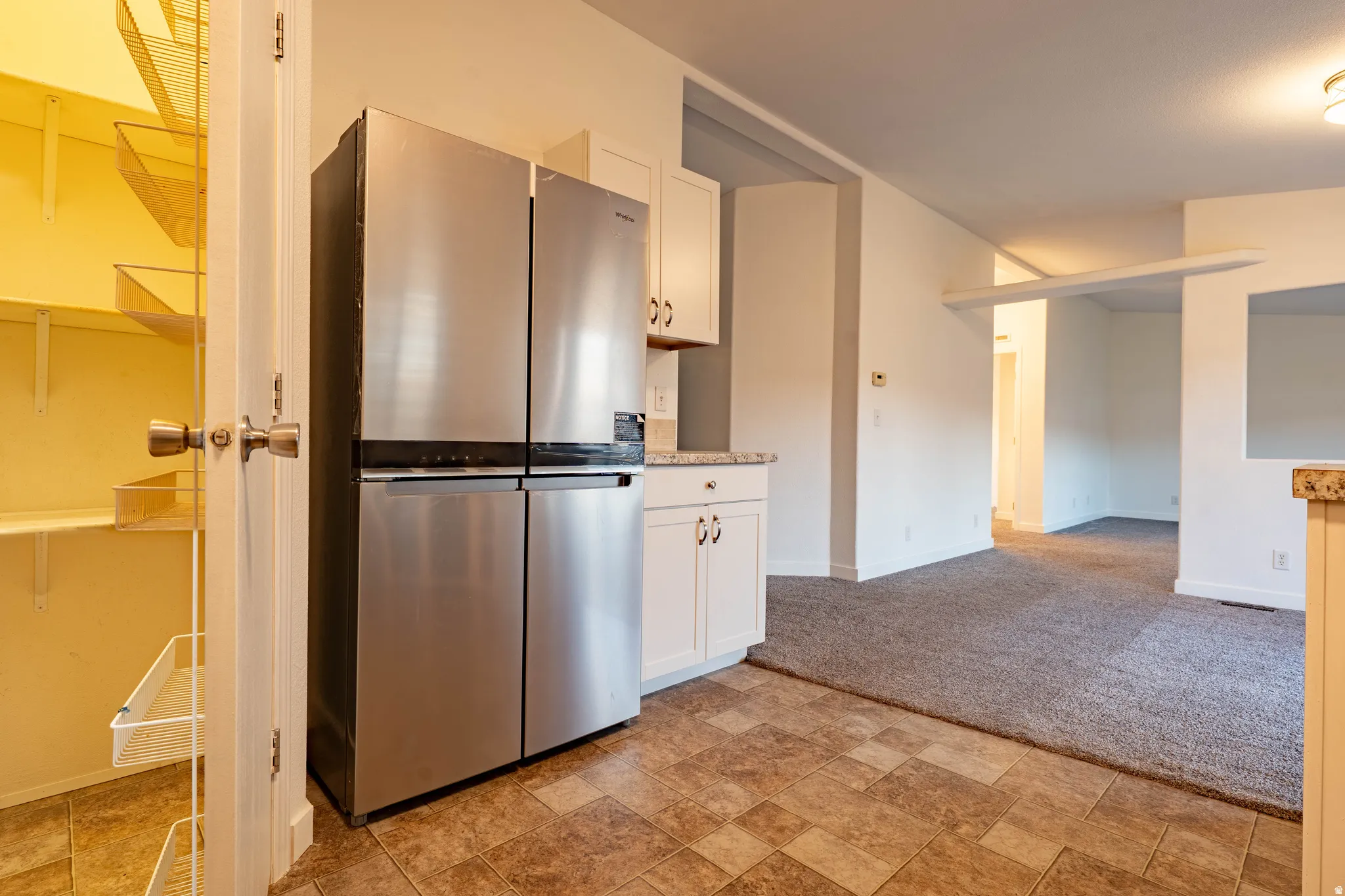 Kitchen featuring patterned tile flooring, white cabinetry, and a built-in pantry with wire shelving