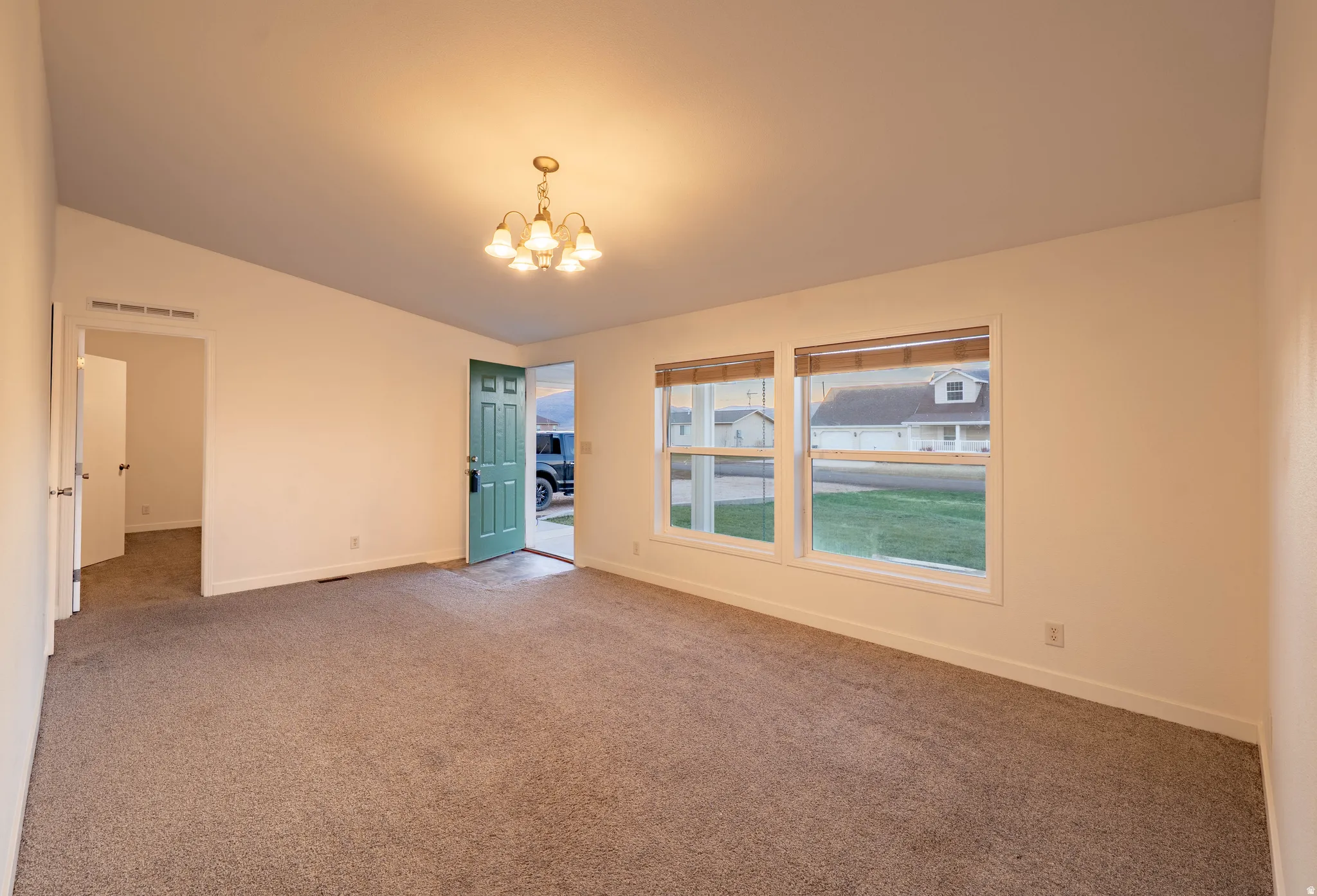 Neutral-toned carpeting, white walls, and a front entry door with a green finish