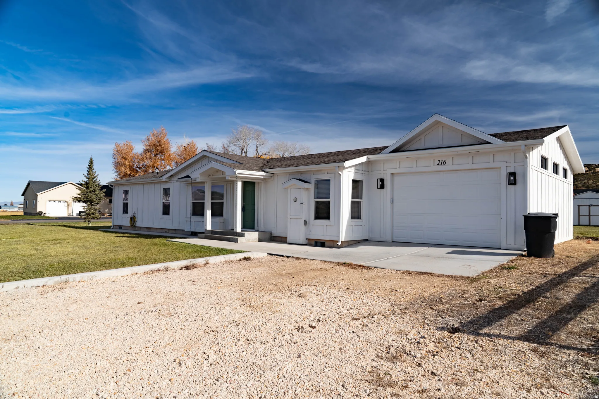 White exterior with board and batten siding, integrated two-car garage, and concrete driveway