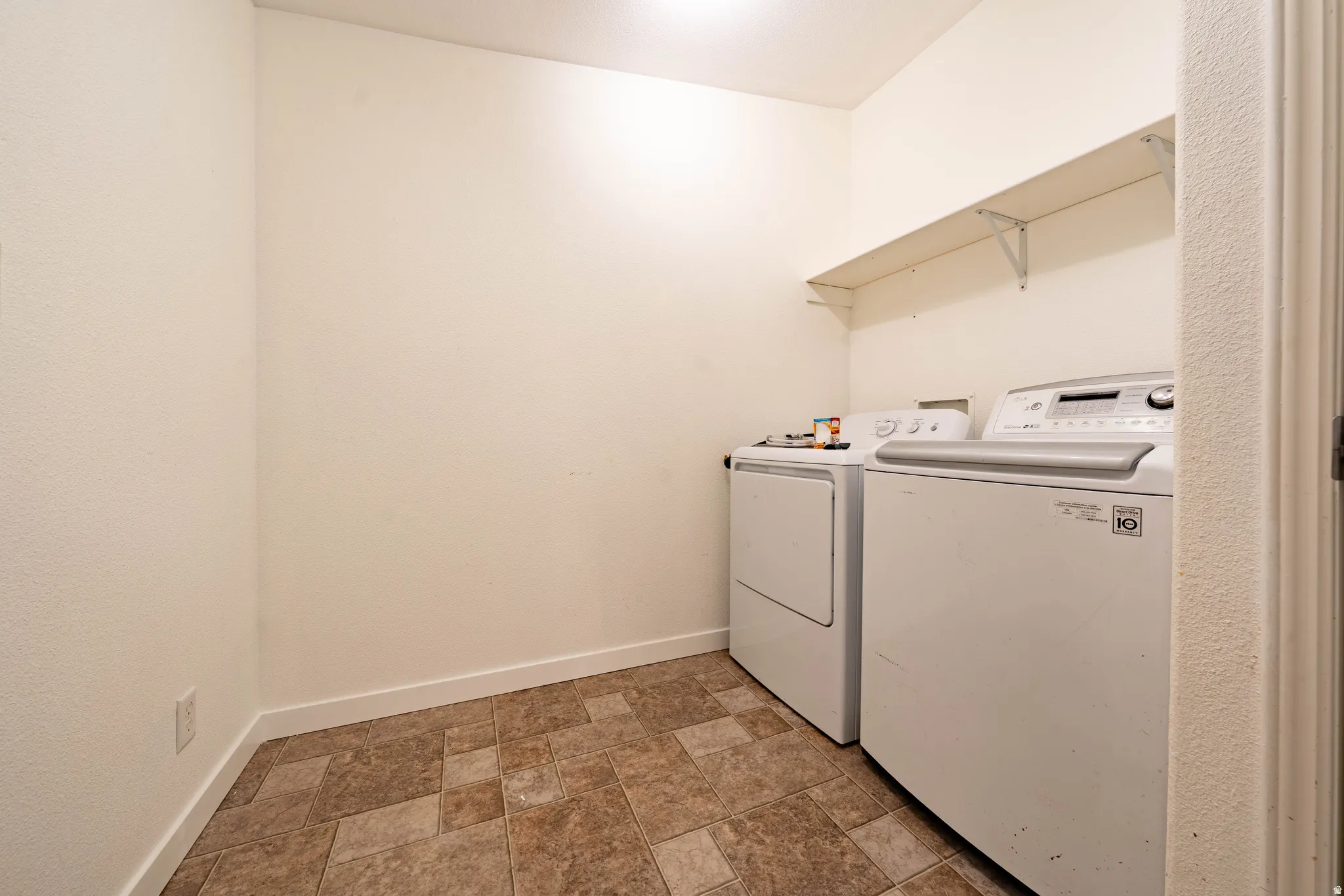 Laundry area with tiled flooring and a wall-mounted shelf