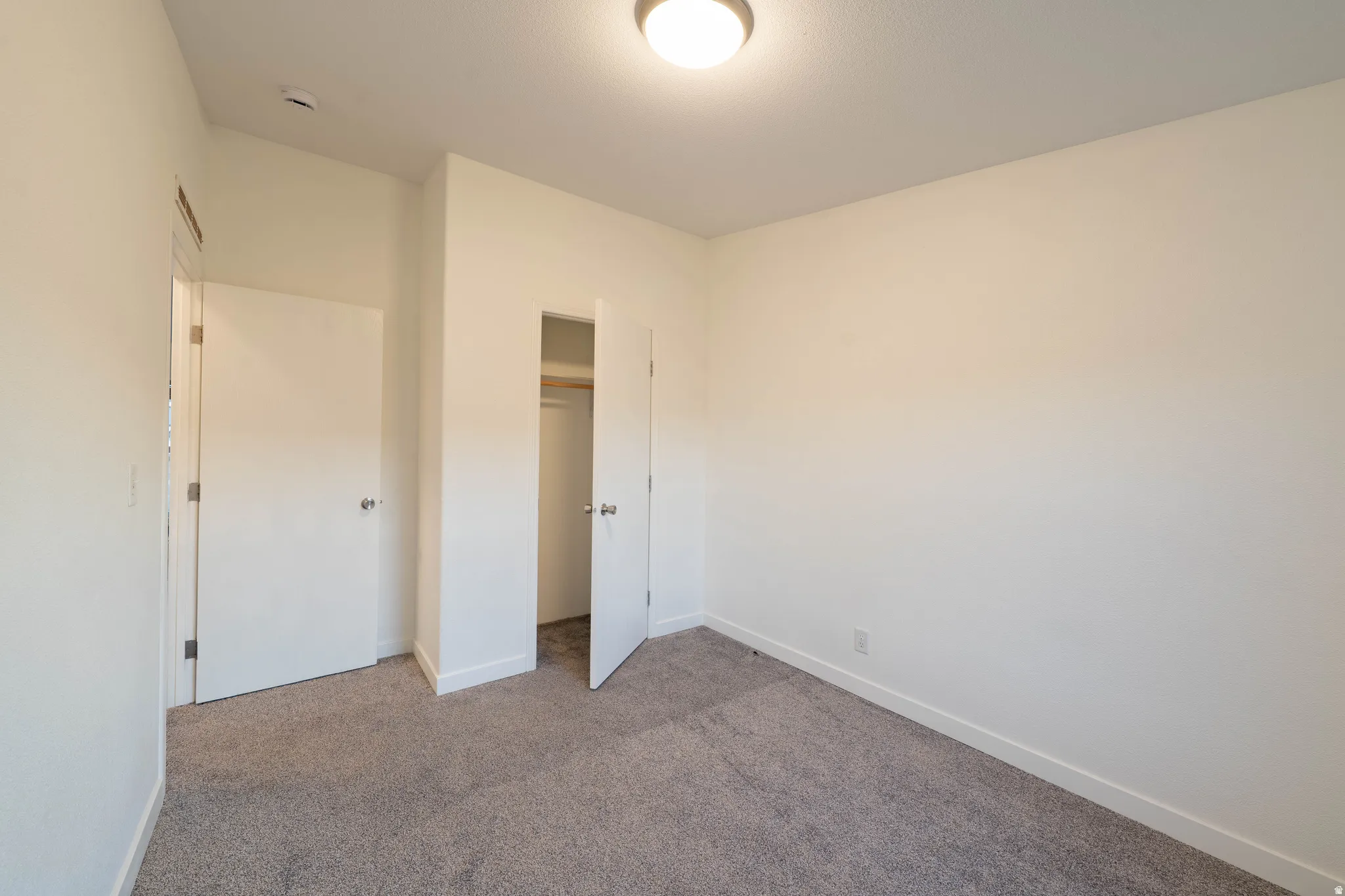 Neutral wall paint, carpeted flooring, flush mount ceiling light, and closet with wood shelving
