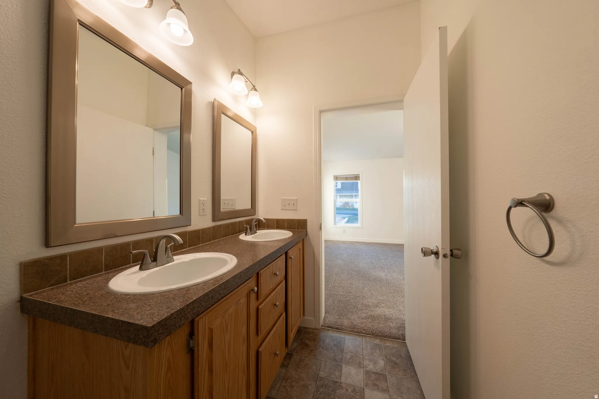 Dual vanity with integrated sinks, wood-finish cabinetry, and framed mirrors