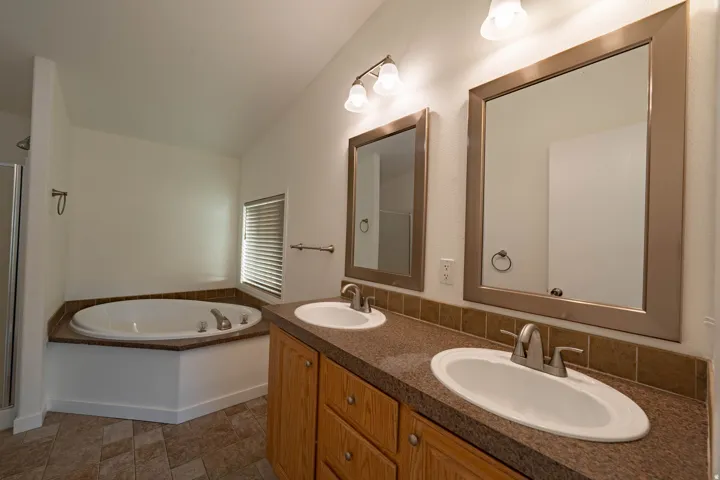 Dual vanity with integrated sinks, framed mirrors, and a built-in jetted tub