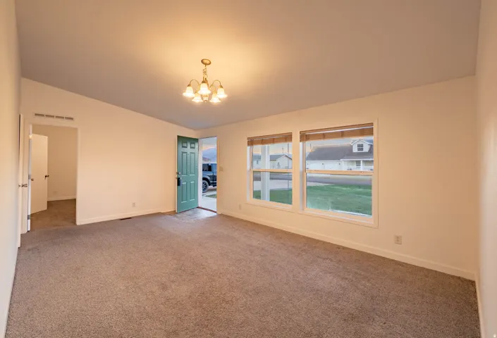 Neutral-toned carpeting, white walls, and a front entry door with a green finish