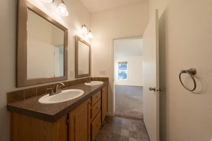 Dual vanity with integrated sinks, wood-finish cabinetry, and framed mirrors