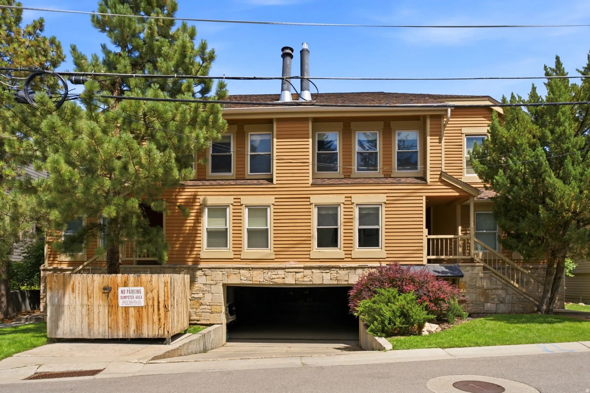 Two-story exterior with horizontal siding, stone foundation, covered entry, front porch with wood railing, and an integrated garage