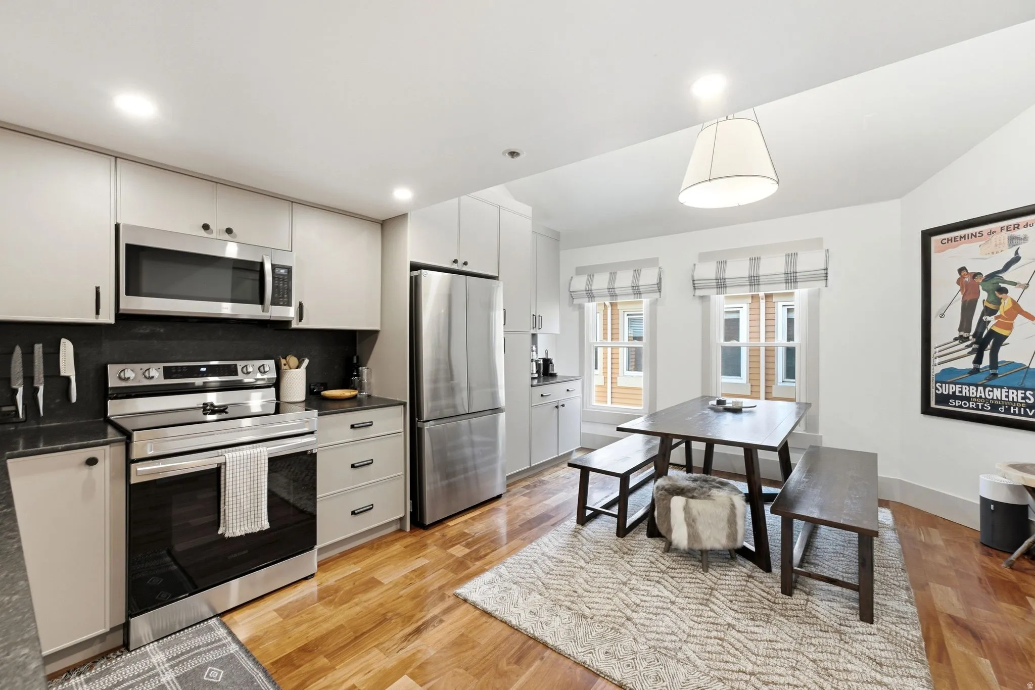 Kitchen featuring stainless steel appliances, light-toned cabinetry, and dark countertops